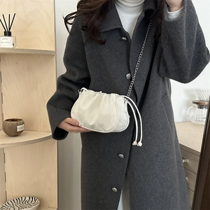 Chic beige pleated pouch bag with silver chain strap worn over a grey wool coat