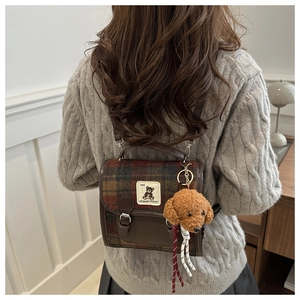 Detail of British vintage plaid backpack with a cute dachshund plush pendant and badge