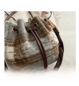 Detail of checkered drawstring bucket bag with woven handle and plush texture fabric
