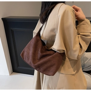 Close-up of a vintage dark brown suede tote bag featuring a wide shoulder strap texture