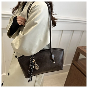 Detail view of dark brown faux leather tote with tennis racket pendant and braided charm