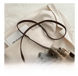 Detail of adjustable brown leather shoulder strap with gold metal buckle on a bucket bag
