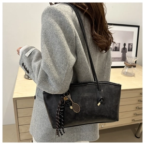 Detail of black leather tote bag with fashion lettering and tennis racket charm