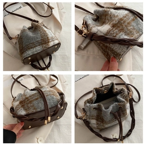 Detail view of plaid plush bucket bag with leather bottom and metal protective studs