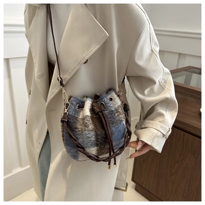 Detail of plaid textured bucket bag with leather drawstring and woven handle shown on model