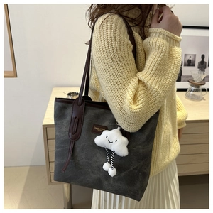 Detail of dark grey canvas tote with brown leather handles and a cute cloud charm