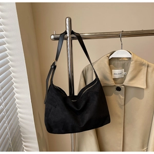Detail of black suede hobo bag with adjustable leather strap and golden hardware accents