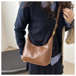 Detail of vintage brown crescent leather bag with adjustable strap and golden buckle