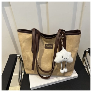Close-up of vintage tote bag detail with brown leather trim and cute cloud charm