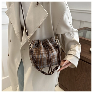 Detail of tweed bucket bag with brown and sky blue checkered pattern and leather drawstring