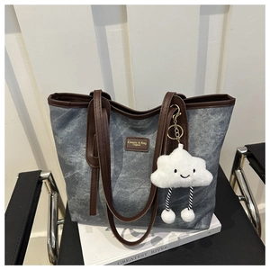 Detail view of retro denim tote bag with brown leather handles and cloud charm on books