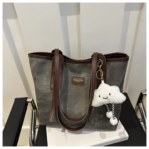 Detail of grey canvas tote bag with brown leather trim and cute white plush cloud charm