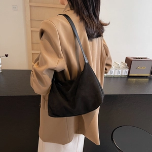 Minimalist black matte suede shoulder bag shown in a stylish modern indoor setting