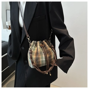 Detail of vintage plaid tweed bucket bag with dark brown leather straps and drawstring