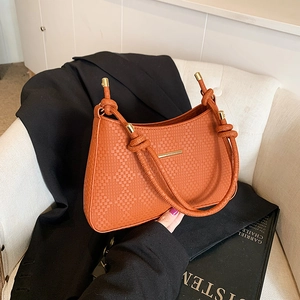 Detail of caramel tote bag with woven texture, cylindrical knot handle and gold hardware
