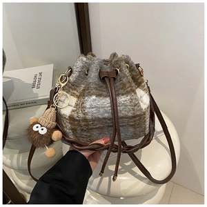 Detail of plaid wool bucket bag with leather drawstring and plush monster charm