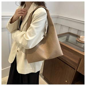 Dettaglio della trama intrecciata della borsa hobo kaki indossata da una modella elegante