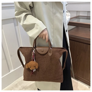 Détail de la texture en daim et du pendentif ours en peluche sur le sac cabas marron