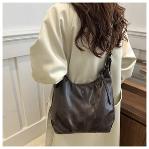 Detail einer weichen dunkelbraunen Tragetasche aus Leder mit Quaste an einem Model