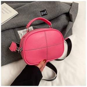 Detailed shot of pink pebble leather pillow bag with silver hardware and wide strap