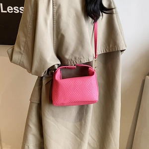 Sac bandoulière rose tissé avec détails dorés et poignée supérieure sur modèle