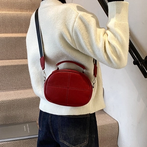 Retro red leather crossbody pillow bag with striped wide strap worn by a model