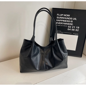 Detail of a black matte leather tote bag featuring long shoulder straps and soft textures
