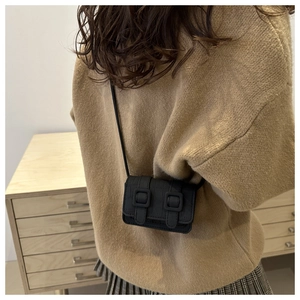 Detail van zwarte mini crossbody tas met krokodillenpatroon en siergespen bij het model