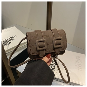 Detail van bruine mini-crossbodytas met krokodillenpatroon en decoratieve vierkante gespen