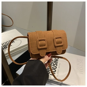 Detail van bruine vintage mini-crossbodytas met dubbele gespen en lederen textuur