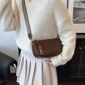 Brown leather saddle bag with patterned strap shown at a 45-degree angle on a model