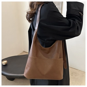 Brown faux leather tote bag showing side view on model with double pocket details