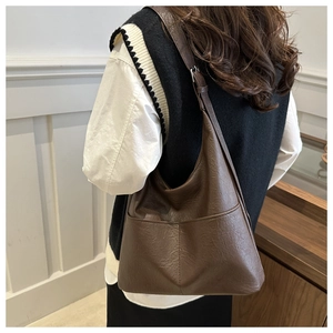 Detail shot of the pebble grain leather texture and side pocket on this brown hobo bag