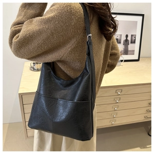 Detail of black leather hobo bag with dual front pockets and silver adjustable buckle strap