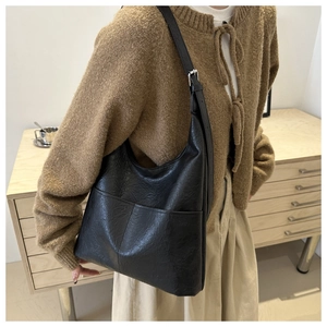 Detail of black textured PU leather tote bag with front pocket and adjustable strap