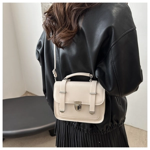 Vista posteriore di una modella con borsa a tracolla color crema in pelle e fibbia argento