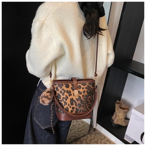 Model trägt Leoparden-Eimertasche mit braunen Trägern und Plüsch-Pompon-Anhänger