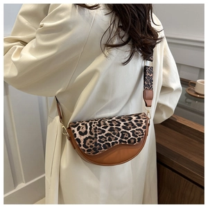 Detail of leopard print flap and gold hardware on retro saddle crossbody bag