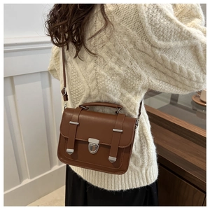 Dettaglio di una borsa a tracolla retrò marrone indossata da una modella in studio