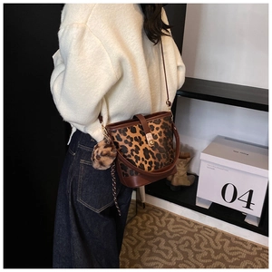 Détail du sac seau léopard avec bandoulière en cuir marron et breloque pompon doux