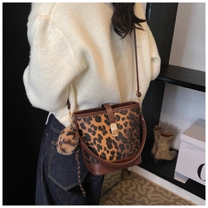 Détail du sac seau à imprimé léopard avec garniture en cuir brun et fermoir doré