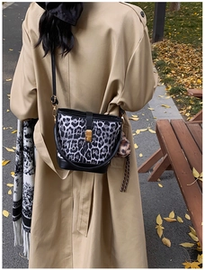 Modische Beuteltasche mit Leopardenmuster und Goldschloss an Model mit khakifarbenem Mantel