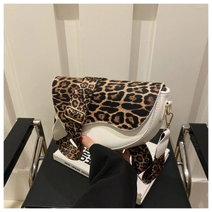 Detail of white saddle bag with leopard print strap and polished gold hardware