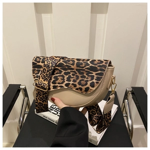 Detail of beige saddle bag featuring leopard print flap and adjustable wide shoulder strap