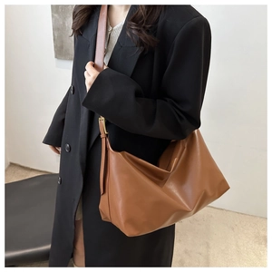 Detail view of caramel brown leather tote bag with wide strap and golden adjustable buckle