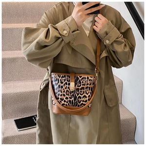 Sac seau léopard tendance avec base en cuir marron porté sur un trench-coat vert