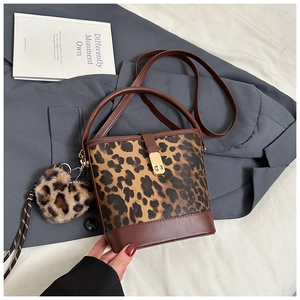Sac seau léopard avec breloque cœur et détails dorés sur fond de blazer gris chic