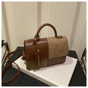 Detail of a brown leather crossbody bag with dual-tone finish and fashion tag accessory