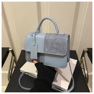 Detail of light blue crossbody bag with silver glitter fabric and fashion charm accessory