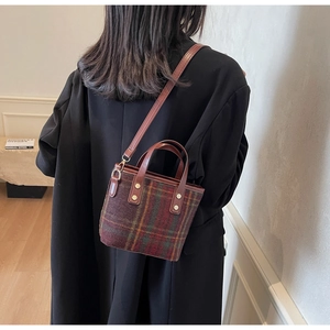 Rear view of a model wearing the vintage plaid wool bucket bag with leather strap